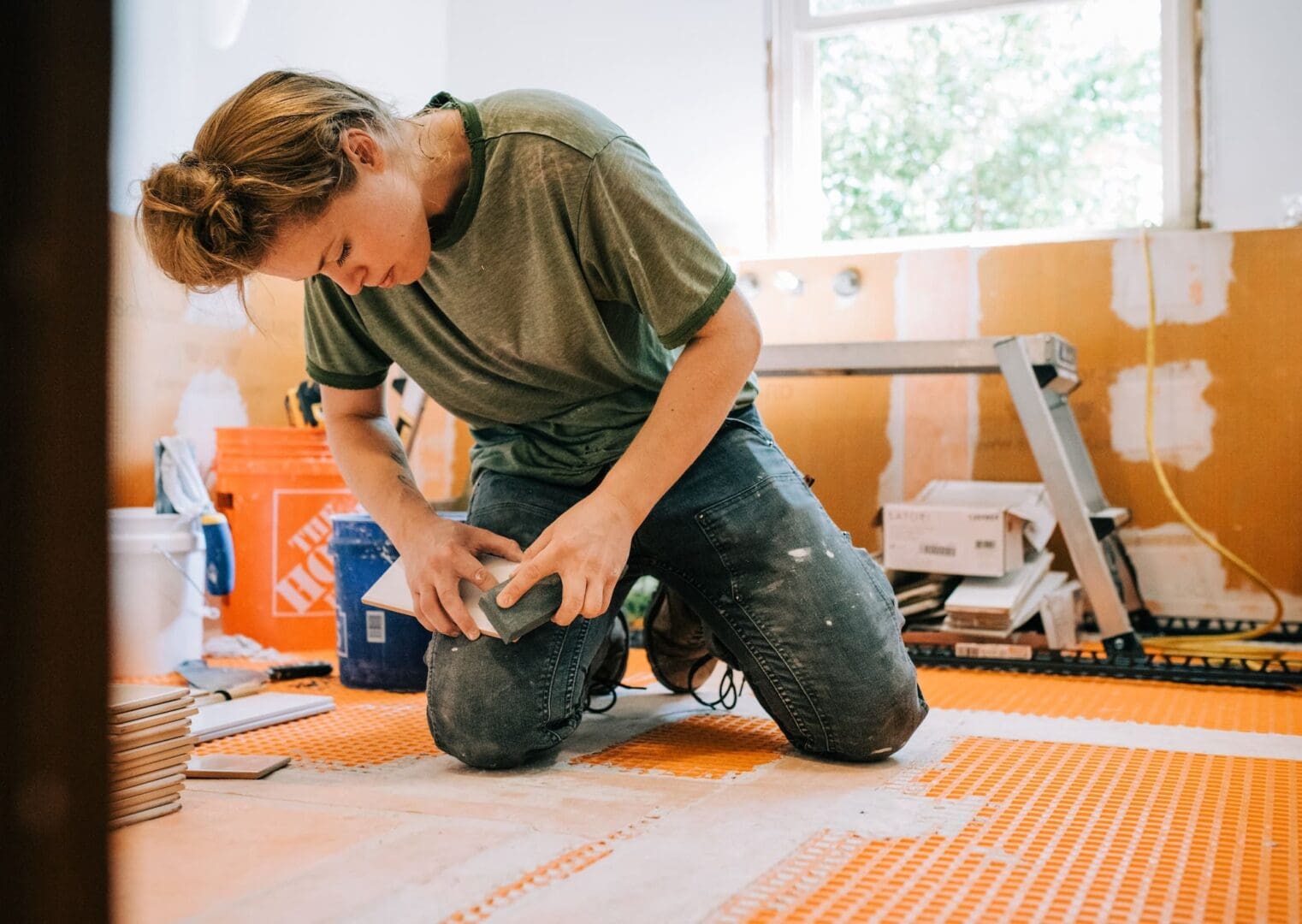 A woman smoothing subway tile edges with a rubbing stone or sanding stone in a bathroom remodel