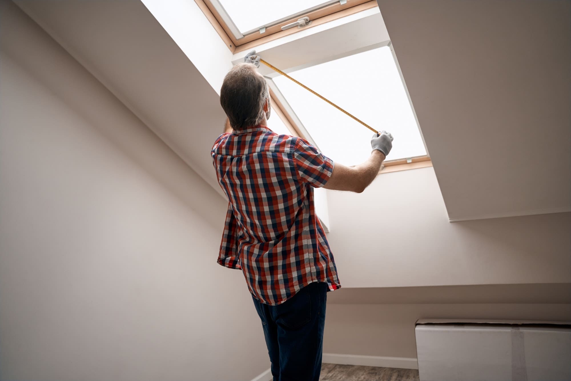 Rear view of repairman measuring skylight window