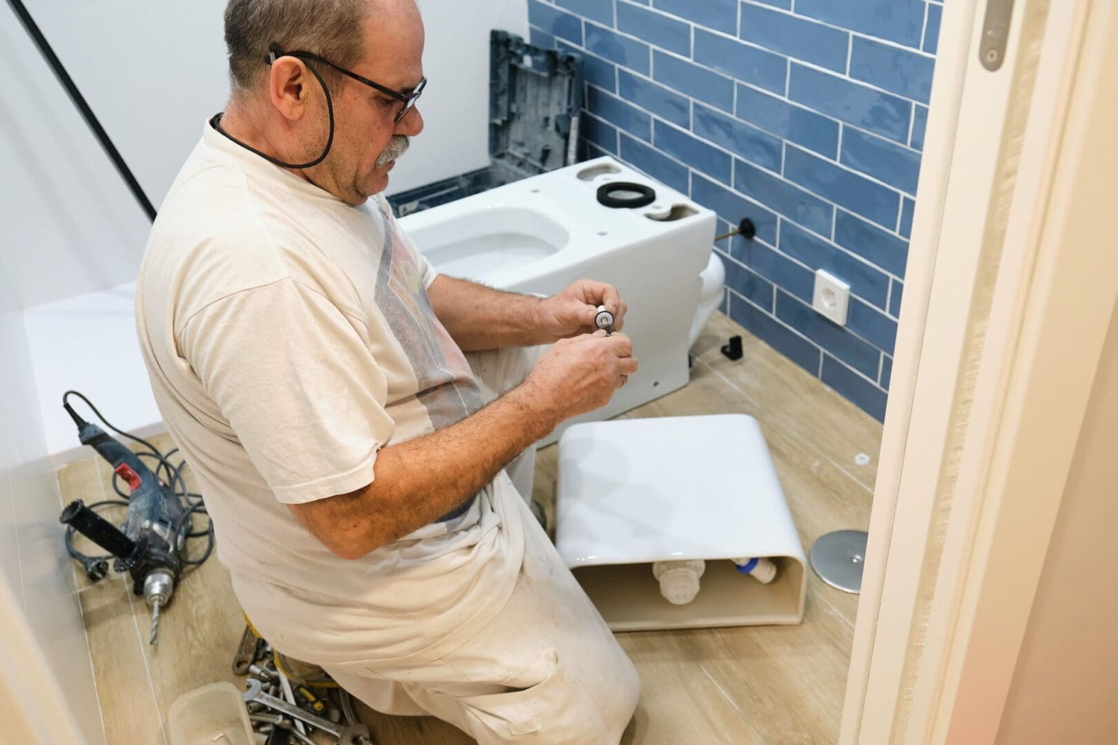 Senior plumber installer installing toilet.